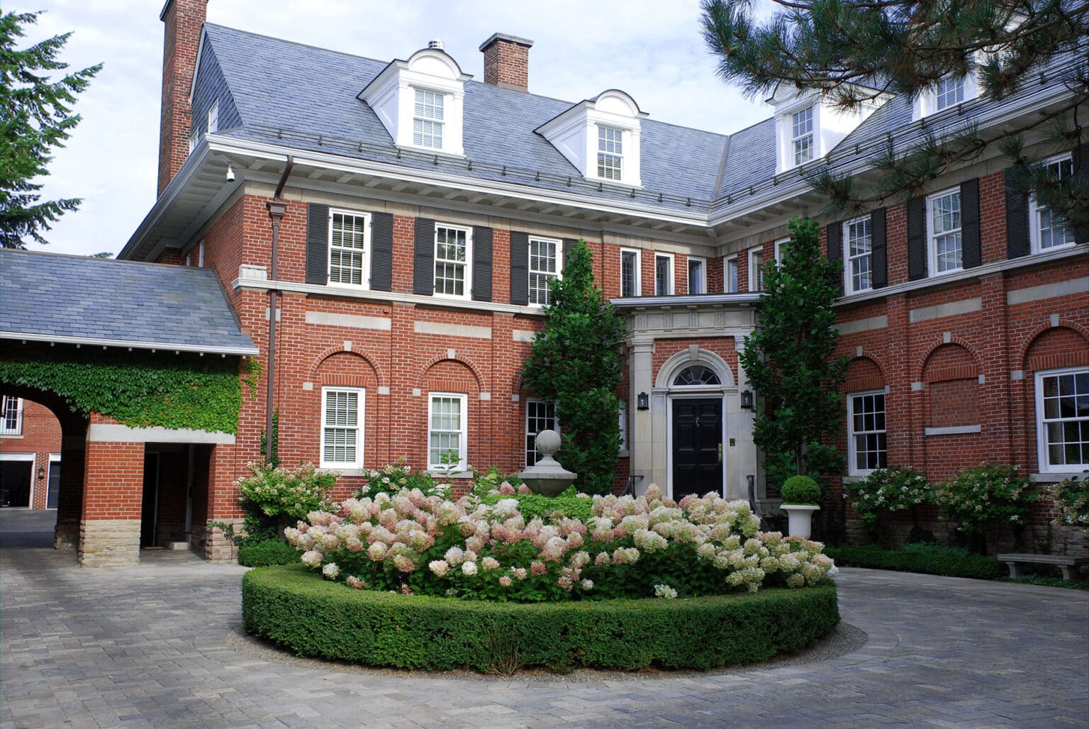 Large house with salte roof, hydrangea in circular driveway.